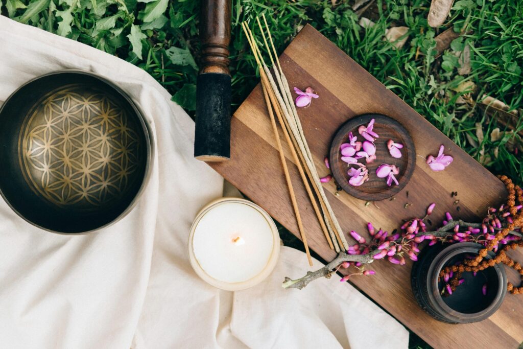 Calming outdoor meditation scene featuring incense, flowers, and a candle on a wooden board.